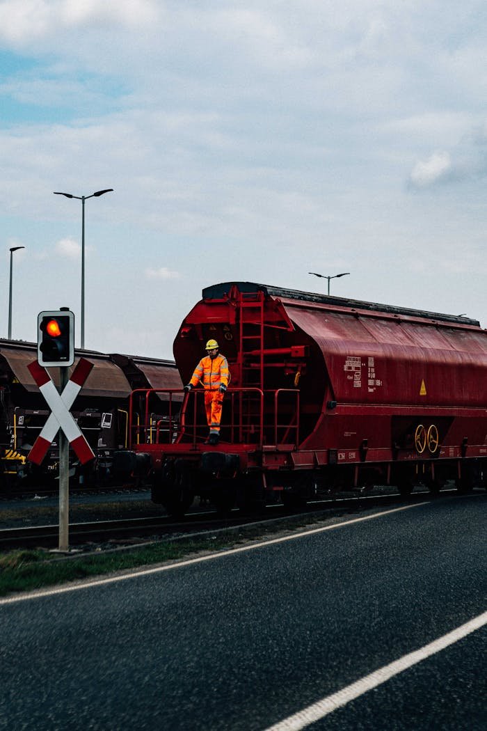 red-freight-train-with-worker-on-railway-crossing-31480093